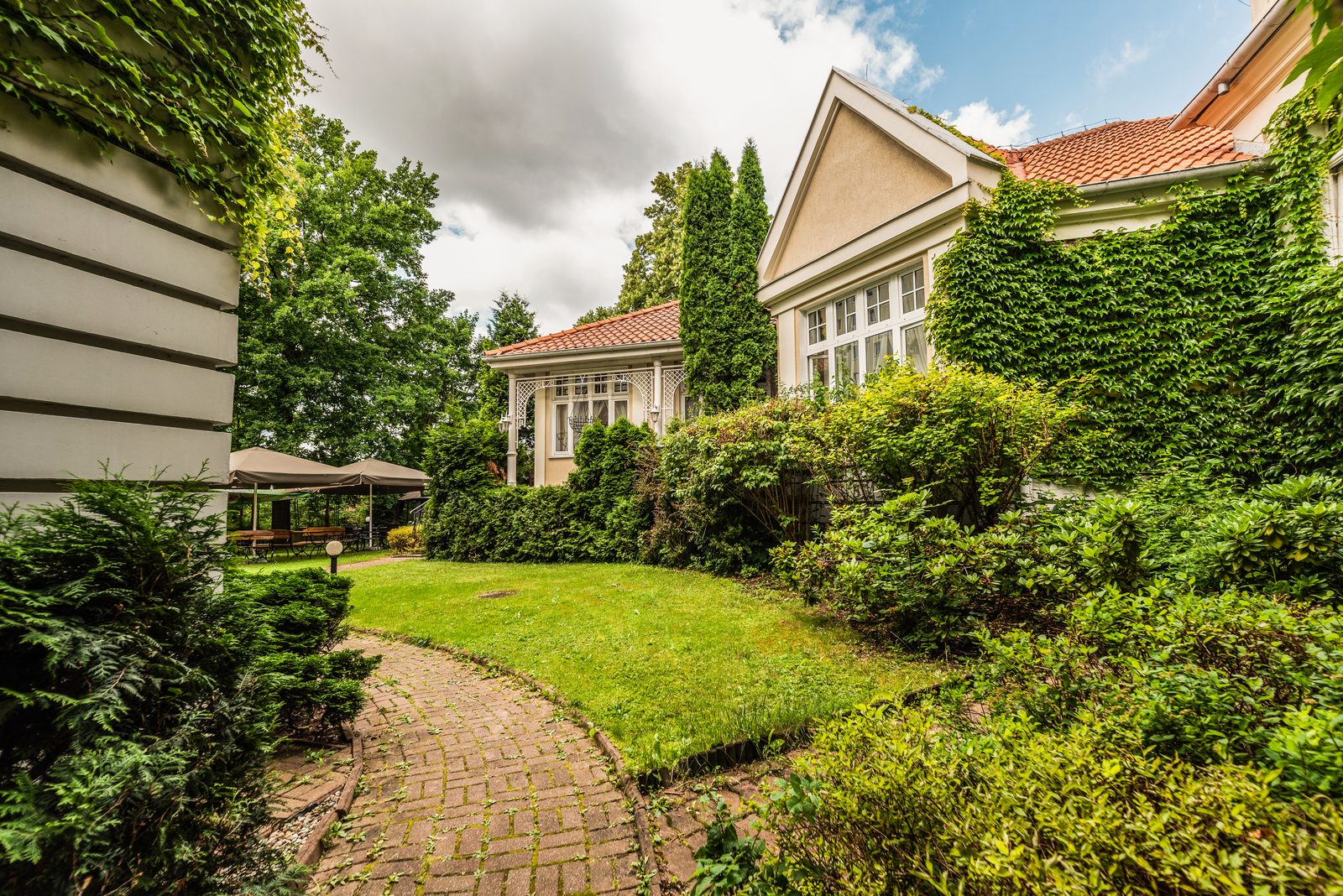 Fasada Villa Pallas pokryta bluszczem i trawnik