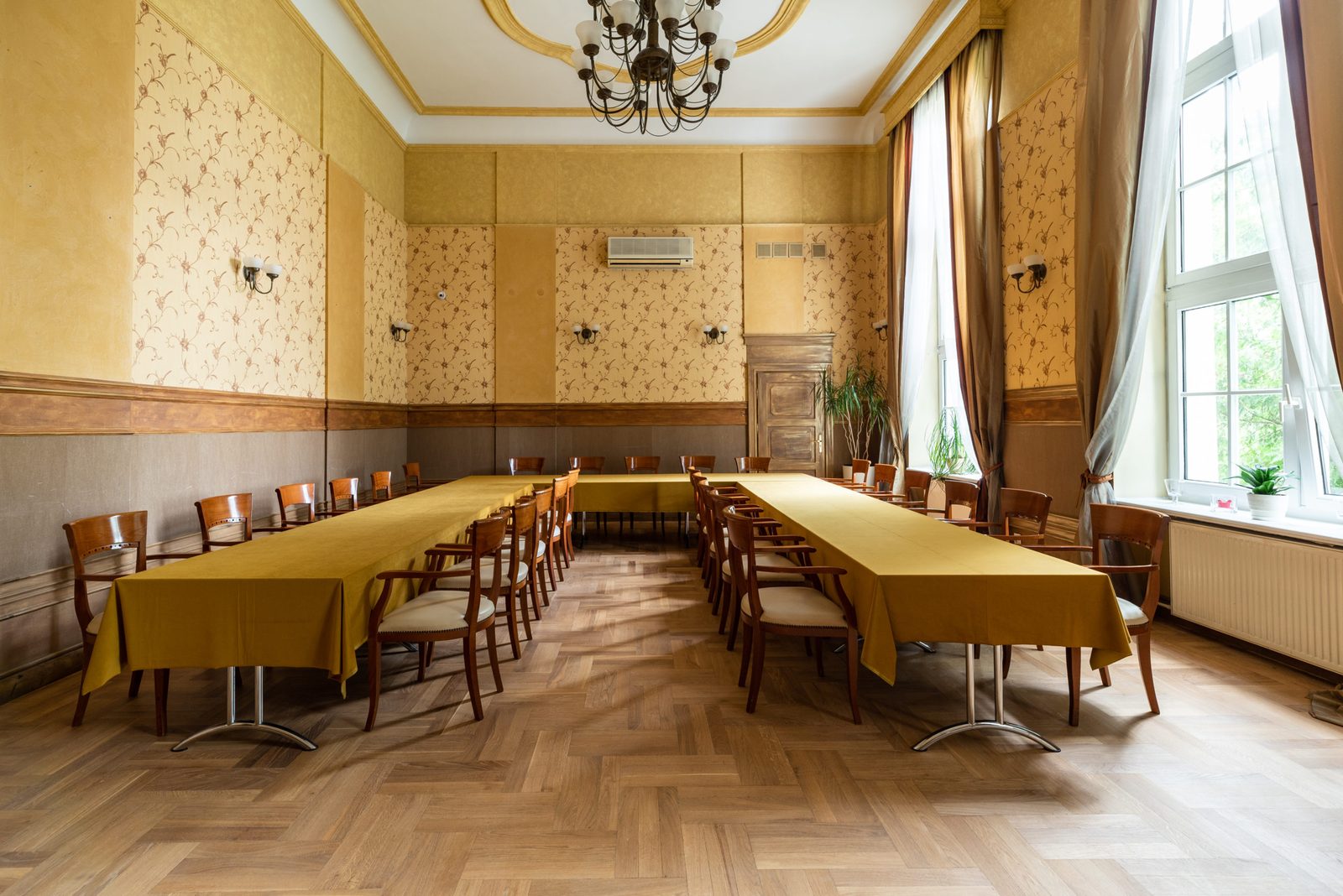 Sala weselna z żółtymi obrusami i żyrandolem